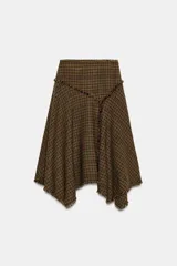 Falda midi de tiro medio con diseño asimétrico y acabados desflecados. Presenta un patrón de cuadros tipo príncipe de Gales en tonos tierra y cierre lateral con cremallera oculta.