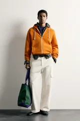 Sudadera con capucha y cierre frontal de cremallera, de corte relaxed fit, confeccionada en tejido de algodón con estructura waffle en color naranja. Cuenta con bolsillos frontales de vivo, cordones ajustables blancos y acabados en rib.