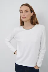 Remera de manga larga en color azul marino, confeccionada en tejido suave. Presenta un delicado detalle de bordado festoneado en color blanco tanto en el cuello redondo como en los puños, aportando un toque distintivo a esta prenda básica.