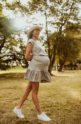 Vestido de maternidad y lactancia color gris claro, de manga corta y escote en V. Confeccionado en algodón elastizado, presenta un diseño con capa superpuesta en el busto para facilitar la lactancia y volados en la falda corta.