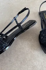 Sandalias chatas de cuero negro, marca Lucy in the Sky, con tira delantera trenzada, puntera cuadrada y tira ajustable al talón.