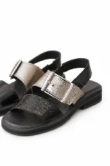 Sandalias de cuero marrón, con diseño de dos fajas amplias, una lisa en la parte delantera y otra superior con hebilla metálica grande y ajustable. Suela plana con plataforma baja y pespunte visible.