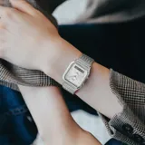 Reloj Casio de estilo vintage con diseño ana-digi, caja de 30mm y esfera plateada. Cuenta con brazalete de acero inoxidable tipo malla milanesa, funciones de hora dual, cronómetro, alarma y calendario automático.