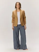 Blazer de lino color negro con pespuntes en contraste de hilo tostado, cuello solapa amplia, cierre frontal con un botón de madera y bolsillos aplicados.