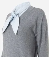 Suéter de punto gris con escote en V y detalle de camisa integrada en color celeste a rayas, con cuello estructurado y lazo frontal. Diseño de corte regular y mangas largas.