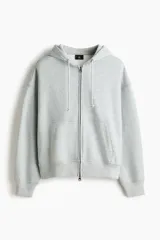 Campera con capucha de H&M, confeccionada en tejido pesado de mezcla de algodón con interior cepillado. Presenta un corte oversized, hombros caídos, cierre frontal completo, bolsillos tipo canguro y cordones ajustables en la capucha.