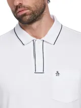 Polo blanco de manga corta con cuello clásico, tapeta de botones y bolsillo en el pecho. Presenta vivos en azul marino en cuello y mangas, y logo de pingüino bordado en el bolsillo.