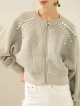 Campera bomber gris confeccionada en tejido combinado de neoprene, con escote bordado artesanalmente con piedras y cierre frontal con cremallera.