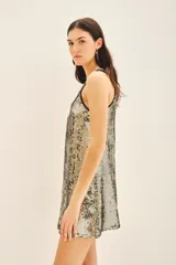 Vestido corto de corte recto y sin mangas, confeccionado en viscosa con bordado integral de lentejuelas en tonos dorados y plateados. Presenta un escote en V con una guarda bordada a mano que incluye piedras, mostacillas y lentejuelas.