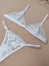 Conjunto de lencería de dos piezas confeccionado en encaje blanco con diseño floral. Incluye un soutien tipo triángulo con tirantes regulables y una bombacha tipo colaless con tiras laterales ajustables.