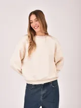 Buzo color beige claro, de cuello redondo y manga larga, con puños y dobladillo acanalados.