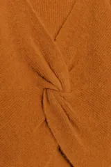 Jersey de punto color naranja quemado, de manga larga y cuello redondo. Presenta un detalle de nudo en la espalda.