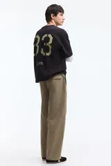 Pantalón relaxed fit en mezcla de algodón, de color beige, con cintura elástica ajustable mediante cordón, bragueta con botón y costuras decorativas giradas en las piernas.