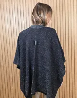 Ruana de tejido de punto de algodón color negro con hilos de lúrex plateados y bordes acanalados en tono gris brillante.