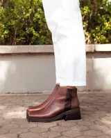 Botinetas de cuero color chocolate, con puntera cuadrada y taco bloque. Presentan un diseño de panel trasero con textura diferenciada y suela de goma robusta.