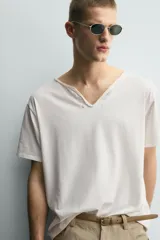 Camiseta de corte relajado con cuello redondo amplio tipo panadero, con detalle de botones y acabado irregular. Manga corta.