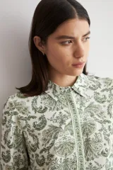 Camisa de manga larga con estampado paisley en tonos verdes sobre base blanca, con cuello camisero y cierre frontal de botones.