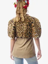 Capa reversible con un lado de piel sintética con estampado animal print y otro lado de tela a cuadros con detalles bordados florales y lazos decorativos. Presenta un diseño estructurado con solapas y borlas con cristales.