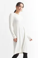 Vestido tejido color blanco, de corte midi, con cuello redondo y mangas largas.
