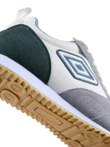 Championes urbanos Umbro modelo Midtown, con diseño de paneles en cuero sintético blanco, gamuza gris y detalle en verde oscuro en el talón. Presenta el logo de la marca en el lateral y suela de goma con textura dentada.