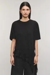 Remera negra de corte oversize, con escote redondo, mangas cortas y detalle de tajo irregular con terminación en puntilla en el ruedo. Confeccionada en jersey de algodón.