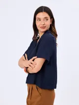 Camisa de manga corta color blanco, confeccionada en mezcla de viscosa, poliamida y lino, con cuello camisero y cierre frontal de botones.
