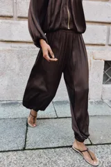 Pantalón de tiro alto con diseño abullonado, confeccionado en tejido satinado con acabado plisado y puños elásticos en los tobillos.