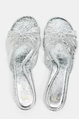 Sandalia plana plateada con tiras cruzadas y detalle de nudo en la parte superior.