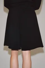 Bermuda de algodón color negro, con tiro medio, cintura elástica ajustable con cordones y bolsillos laterales ocultos en la costura.