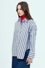 Camisa de manga larga con diseño a rayas verticales en tonos celestes y amarillos sobre fondo blanco, cuello camisero clásico y cierre frontal de botones.