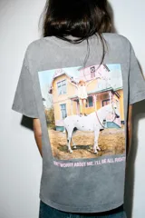 Camiseta de algodón con efecto lavado en color gris, de corte regular, cuello redondo y manga corta. Presenta un pequeño estampado frontal con el logo de Pippi Långstrump y una gran estampación gráfica en la espalda.