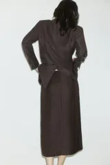 Pollera midi de sastre color marrón oscuro, tiro alto, corte recto con tajo frontal. Presenta cierre y corchete ocultos, y bolsillos al bies.