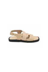 Sandalias planas Paddock Noma de color beige, con tiras cruzadas en el empeine y diseño grabado símil cocodrilo combinadas con tiras lisas. Cuentan con tira ajustable en el talón con hebilla metálica y suela plana en color negro con punta cuadrada.