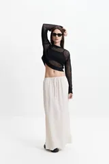 Falda larga color crema, de corte recto y cintura elastizada con lazo ajustable.