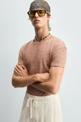 Camiseta de algodón con cuello redondo y manga corta, confeccionada en tejido jacquard a rayas horizontales en tonos terracota y beige.