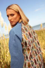 Campera de jean con mangas de denim azul y espalda confeccionada en tejido con diseño geométrico multicolor.