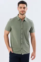 Camisa de piqué lisa color celeste, de manga corta, con cuello camisero y cierre frontal de botones oscuros.