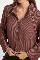 Sweater de punto acanalado color camel, con cuello alto y cierre frontal parcial. Presenta mangas largas con costuras raglán y un corte ligeramente cropped.