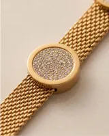 Pulsera rígida de acero con baño dorado, de diseño mallado, con tres dijes circulares incrustados con detalles en ónix, nácar y circonias.
