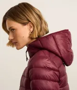 Campera puffer deportiva de mujer, confeccionada en tejido tecnológico ligero con relleno acolchado. Presenta capucha integrada, cierre frontal con cremallera y diseño de manga larga. La prenda destaca por su versatilidad, siendo capaz de transformarse en una pequeña cartera.