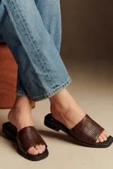 Sandalia tipo chinela de cuero marrón con textura trenzada, base plana y puntera cuadrada.