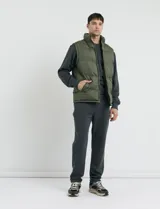 Chaleco capitoneado color verde militar, con cuello alto, cierre frontal y bolsillos laterales. Presenta un diseño acolchado con costuras horizontales.