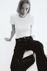 Jeans de cinco bolsillos en denim de algodón con leve stretch, color azul oscuro. Modelo de corte ajustado de cintura a muslo, más holgado de rodilla a bajo, con pierna acampanada (corte para bota) y tiro alto con cierre y botón.