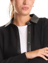 Sobrecamisa de mujer marca Sioni, con diseño combinado en tejido de punto y eco cuero. Presenta cuello camisero, cierre frontal con botones y mangas largas con puños tejidos.