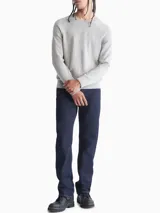 Sweater de punto liso color gris melange, con cuello redondo y puños y dobladillo en punto canalé. Presenta un pequeño logo bordado en el pecho.