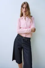 Chaqueta de punto color rosado con cuello polo, manga larga y cierre frontal con botones.