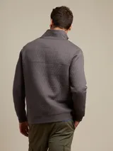 Sweater azul marino con cuello alto abotonado, diseño acolchado y bolsillo tipo canguro.