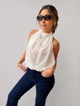 Blusa de gasa color blanco con escote halter y frunce delantero. Presenta un diseño fluido con espalda descubierta y tiras para atar.