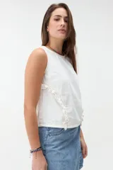 Blusa de denim blanco sin mangas, con cuello redondo y volados a lo largo de las costuras laterales.
