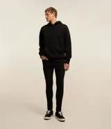 Pantalón skinny jean negro de corte ajustado, con diseño de cinco bolsillos y trabillas para cinturón.